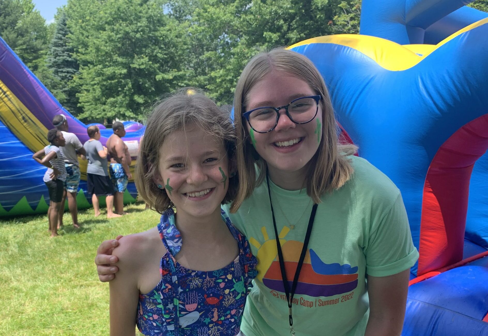 a student leader posing with a student infront of bouncy houses that are outside